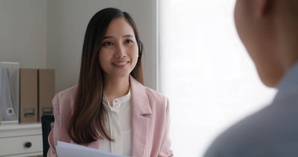 HR manager in Singapore office discussing payroll software vs. outsourcing options.